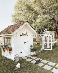 a small white shed sitting on top of a lush green field