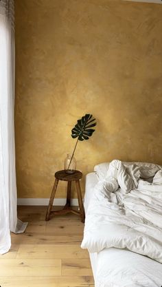 a bed sitting next to a window with a plant on it's headboard