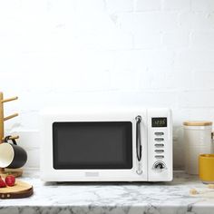 a white microwave oven sitting on top of a counter next to other kitchen accessories and utensils