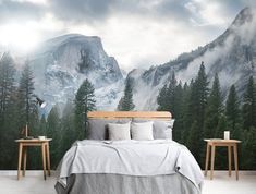 a bedroom with mountains and trees painted on the wall, along with two nightstands