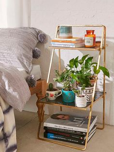 a bed room with a neatly made bed and a plant on a shelf next to the bed