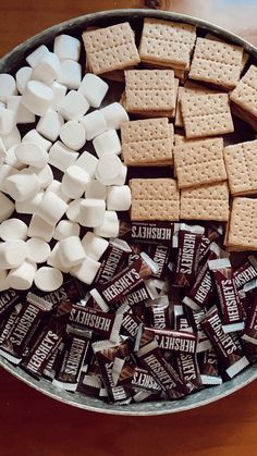 a metal bowl filled with marshmallows and graham's crackers on top of a wooden table