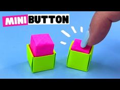 a hand is pushing the button on two cubes that are colored pink and green