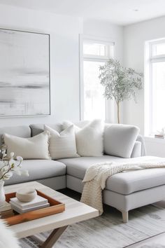 a living room with white furniture and large windows in the back ground, along with a rug on the floor