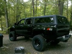 a black truck is parked in the woods