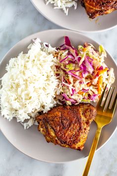 two plates with rice, meat and coleslaw on them next to a fork