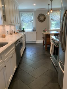 a large kitchen with white cabinets and stainless steel appliances, along with tile flooring