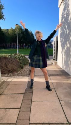 a woman in a kilt posing for the camera with her hands up and arms outstretched