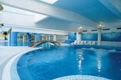 an indoor swimming pool with blue water and steps leading up to the top of it