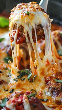 a close up of a slice of pizza being lifted from a pan with meatballs and cheese on it