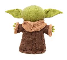 a knitted yoda doll wearing a brown sweater and scarf on a white background