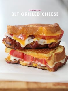 two grilled cheese sandwiches stacked on top of each other with bacon, tomato and melted cheese