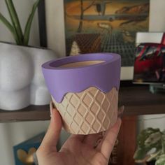 a person holding up a cup with ice cream inside it in front of a shelf