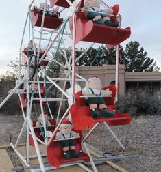 two santa claus dolls sit on a ferris wheel ride at an amusement park in the desert