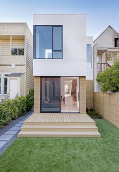 a modern house with an outdoor deck and grass area