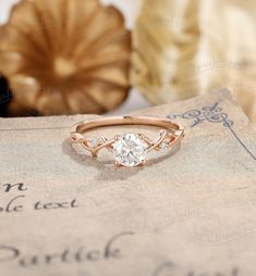 a rose gold engagement ring with an oval diamond in the center on top of a piece of paper