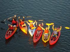 a group of people riding on top of kayaks in the water with paddles