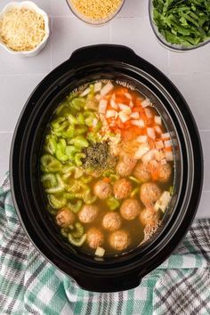 an overhead view of a bowl of soup with meatballs, broccoli and carrots