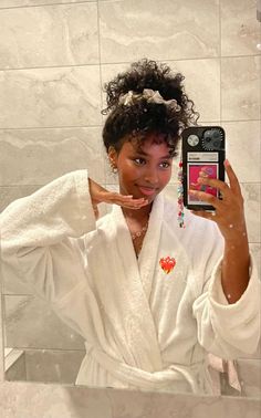 a woman taking a selfie in front of a bathroom mirror with her cell phone