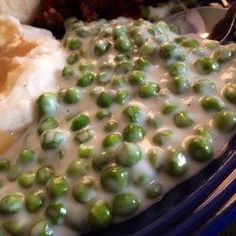 a plate with peas, bread and mashed potatoes covered in gravy on it