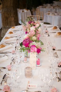 the table is set with silverware and pink flowers