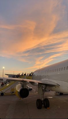 an airplane is sitting on the tarmac at sunset