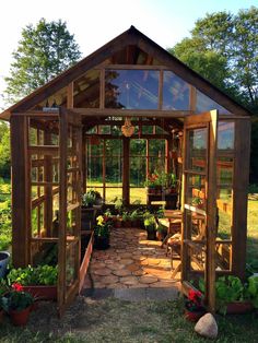 a small wooden greenhouse with lots of plants in it