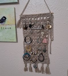 Here's a unique way to store while displaying your collection of earrings. Cross between light gray and taupe color crochet window pane pattern  Avoid earrings getting caught in yarn, silver jump rings stitched in. Holds 31 pair of hoop or dangle style earring. 12 inches long not including hanging loop or fringe 6 1/2  inches wide  Little pocket for holding stud earrings, earring backs, bracelets or necklaces Also can be displayed as wall art. Machine wash  warm, dry low heat Great gift for a teen, college dorm or small apartment dweller Ktochetlady original design, © 2023, all rights reserved. Crochet Wall Hanging, Hanging Earring, Gray Crochet, Earrings Cross, Crochet Wall Hangings, Jewelry Hanger, Design 2023, Hanging Jewelry, Earring Holder