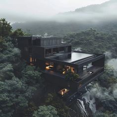 an aerial view of a house in the middle of a forest with trees and fog