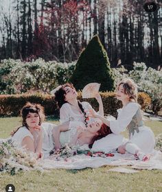 three women sitting on a blanket in the grass