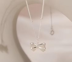 This charming silver bow pendant necklace is a perfect blend of elegance and simplicity. Featuring a delicate ribbon charm crafted from high-quality sterling silver, this necklace is designed to add a touch of sophistication to any outfit. Its minimalist design makes it versatile enough for everyday wear or as a special accessory for a formal event. Whether you're looking for a gift for a loved one or a treat for yourself, this dainty necklace is sure to delight. Features Color: Silver Material: Sterling Silver Closure: Lobster clasp Style: Minimalist, Elegant, Everyday Wear Bow Pendant, Bow Style, Silver Bow, Style Minimalist, Dainty Necklace, Formal Event, Pendant Necklaces, Minimalist Design, Necklace Etsy