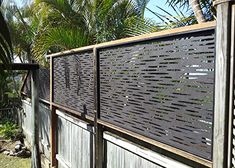 a wooden fence with metal slats on it and palm trees in the back ground