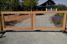 a wooden gate with metal bars on the top and bottom, in front of a house