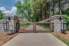 a gated entrance to a home with stone walls and gates leading into the yard