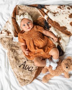 a baby laying on top of a blanket next to a stuffed animal