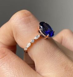 a woman's hand holding a blue and white diamond ring