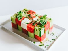 slices of cucumber and watermelon arranged on a white plate with herbs