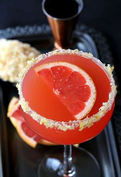 a grapefruit margarita with sugar garnish on the rim and an orange slice