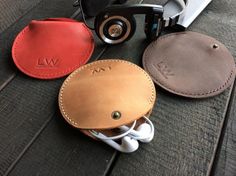 three leather cases sitting on top of a wooden table next to a pair of glasses