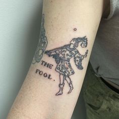 a woman with a tattoo on her arm that reads the fool and has an umbrella