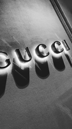 the word gucci is lit up in black and white with light reflecting off it