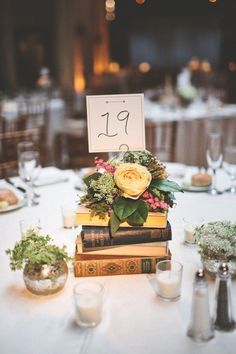 a stack of books sitting on top of a white table covered in flowers and greenery