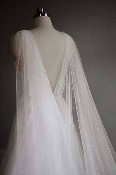 the back of a wedding dress with white sequins on it and a long veil