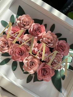 there are many pink flowers in the box that is decorated with gold letters and leaves