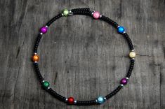 a black beaded bracelet with multicolored beads and silver clasp on a wooden surface