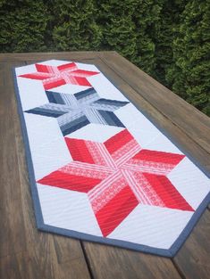 a red, white and blue quilted table runner on top of a wooden deck