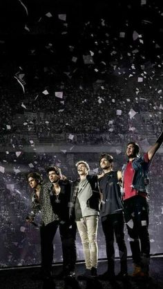 a group of young men standing next to each other on top of a stage with confetti in the air