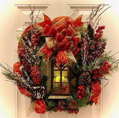 a christmas wreath with pine cones, evergreens and red ribbon hanging on the front door