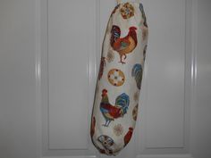 an oven mitt with roosters on it hanging from a hook in front of a door