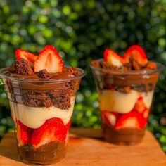 two dessert cups with strawberries and chocolate on top